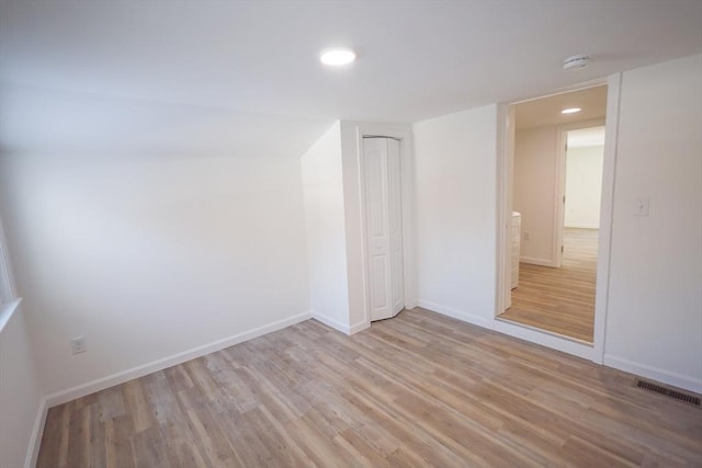 unfurnished room featuring lofted ceiling and light wood-type flooring