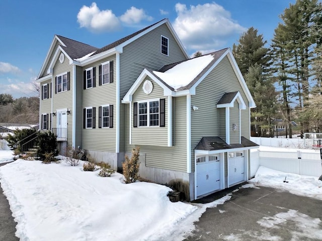 view of snow covered exterior with a garage and fence