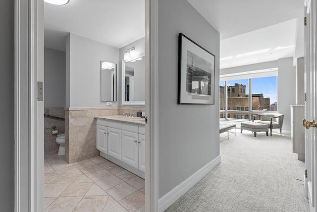 bathroom with toilet, vanity, tile patterned floors, and tile walls