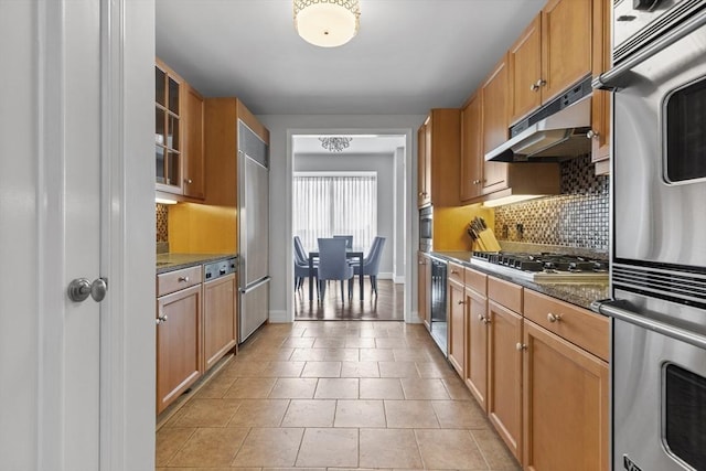 kitchen with tasteful backsplash, dark stone countertops, beverage cooler, and appliances with stainless steel finishes