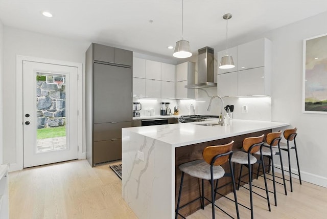 54-58 Robey St Unit 54, Boston, MA 02119 - kitchen featuring wall chimney range hood, a peninsula, modern cabinets, light wood finished floors, and recessed lighting