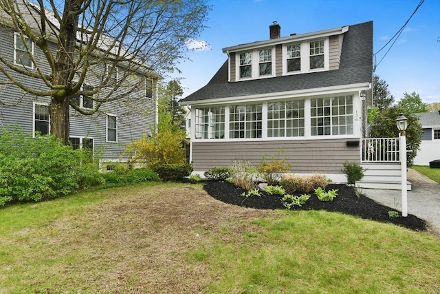 exterior space featuring roof with shingles, a chimney, and a front yard