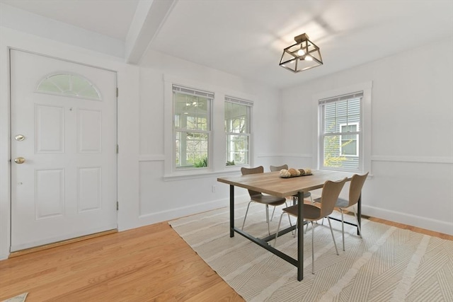 dining space featuring baseboards, beam ceiling, and light wood-type flooring