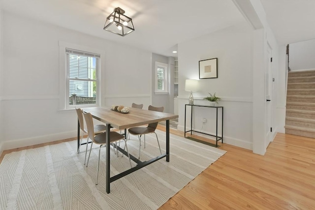 dining room with light wood-type flooring, stairway, and baseboards