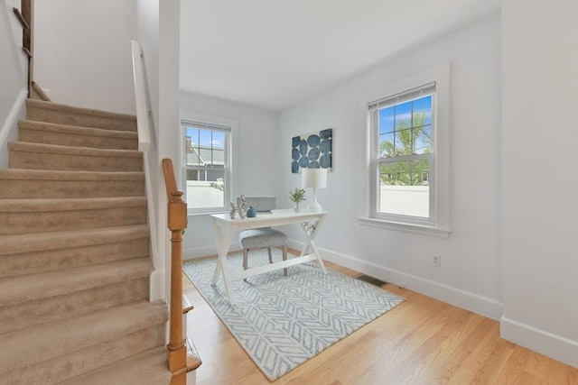 office area with baseboards, a wealth of natural light, visible vents, and wood finished floors
