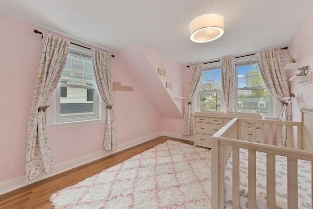 unfurnished bedroom featuring baseboards, multiple windows, and wood finished floors