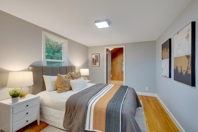bedroom featuring ensuite bath, wood finished floors, and baseboards