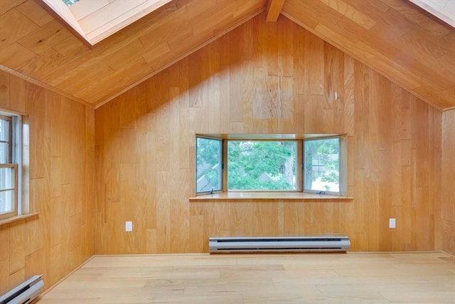 unfurnished room with a wealth of natural light, wood walls, a baseboard radiator, and vaulted ceiling with skylight