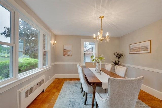 dining area with radiator, an inviting chandelier, a wealth of natural light, and baseboards