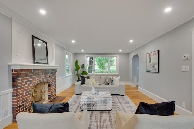 living area with crown molding, light wood-type flooring, and arched walkways