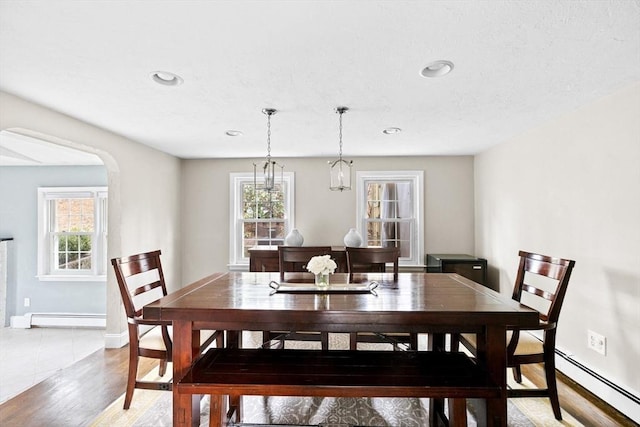 dining area with a wealth of natural light, light wood-style flooring, a baseboard heating unit, and baseboard heating