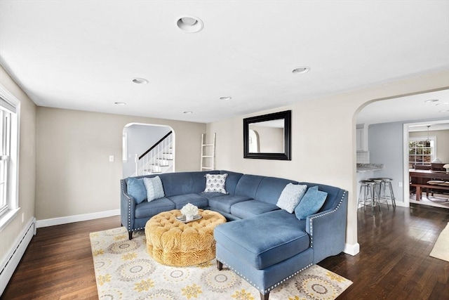 living room with arched walkways, baseboards, a baseboard heating unit, and wood finished floors