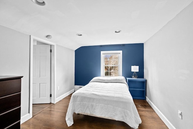 bedroom with baseboards, lofted ceiling, and wood finished floors