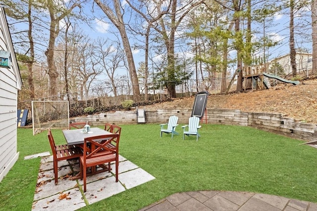 view of yard featuring a fenced backyard, outdoor dining area, a patio area, and a playground