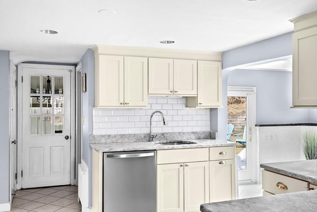 kitchen with light tile patterned flooring, light stone counters, a sink, tasteful backsplash, and stainless steel dishwasher