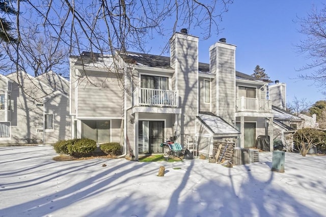 snow covered back of property with a balcony