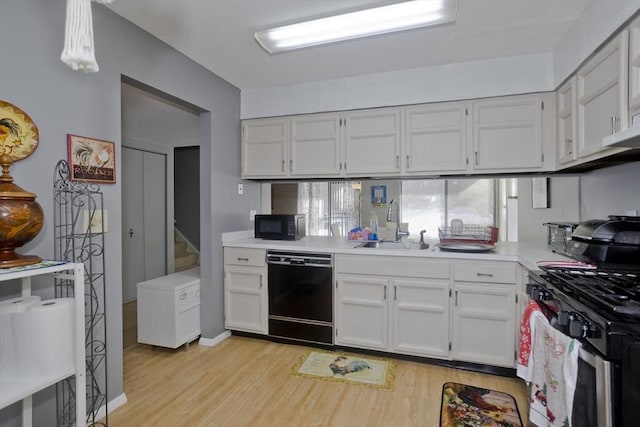 kitchen with light wood-type flooring, white cabinets, sink, and black appliances