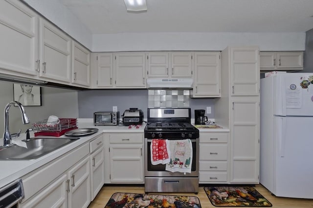 kitchen featuring sink, white refrigerator, stainless steel range with gas cooktop, dishwasher, and white cabinets