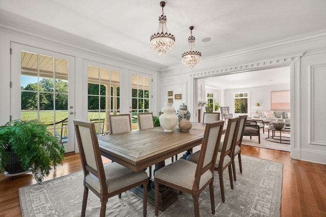 dining area with an inviting chandelier, hardwood / wood-style flooring, french doors, and ornamental molding