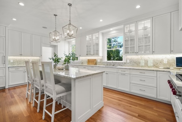 kitchen with an inviting chandelier, light hardwood / wood-style floors, white cabinetry, and a kitchen island