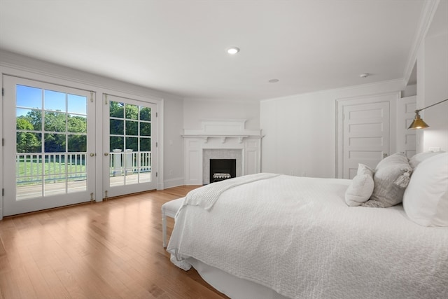 bedroom with light hardwood / wood-style floors, access to outside, and crown molding