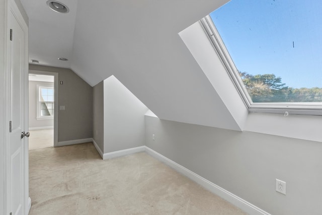 additional living space featuring lofted ceiling with skylight and light colored carpet