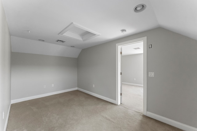 additional living space featuring vaulted ceiling and light colored carpet