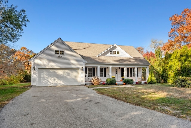 view of front of house with covered porch, a front yard, and a garage