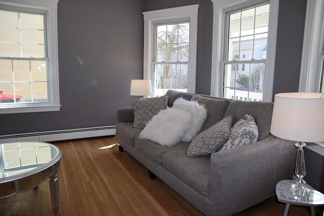 living area with wood finished floors, a baseboard heating unit, and plenty of natural light