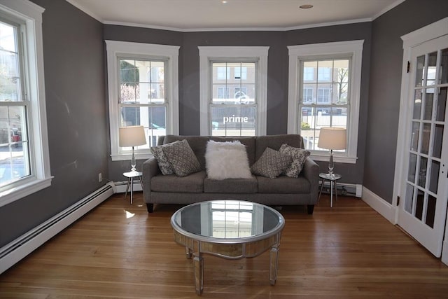 living room with wood finished floors, crown molding, and a baseboard heating unit