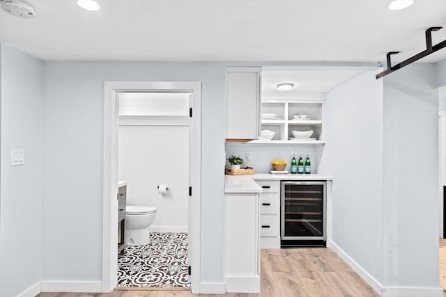 bar featuring beverage cooler, a barn door, baseboards, light wood-style flooring, and recessed lighting