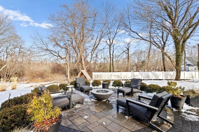 snow covered patio featuring an outdoor fire pit and fence