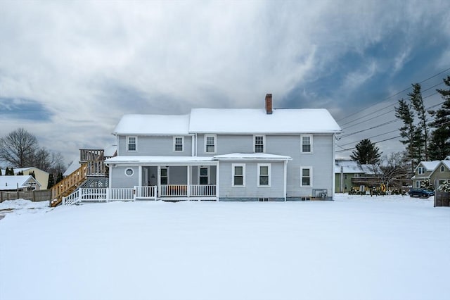 snow covered property with a porch and a chimney