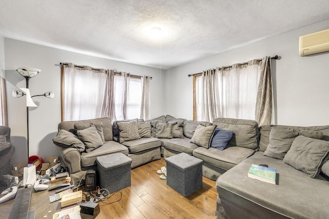 living area featuring a textured ceiling, a wall unit AC, and hardwood / wood-style floors