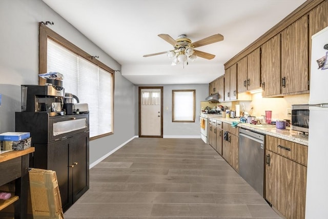 kitchen with baseboards, under cabinet range hood, appliances with stainless steel finishes, brown cabinetry, and dark wood-style flooring