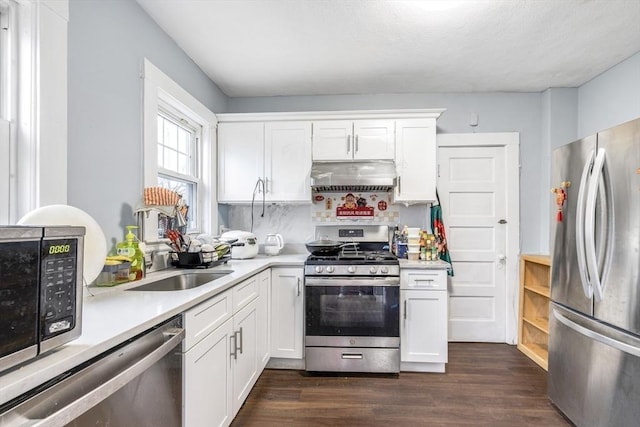 kitchen featuring light countertops, dark wood-type flooring, under cabinet range hood, appliances with stainless steel finishes, and white cabinetry