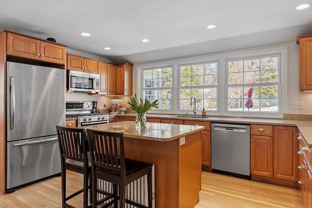 kitchen featuring appliances with stainless steel finishes, a breakfast bar area, a sink, and light wood-style flooring