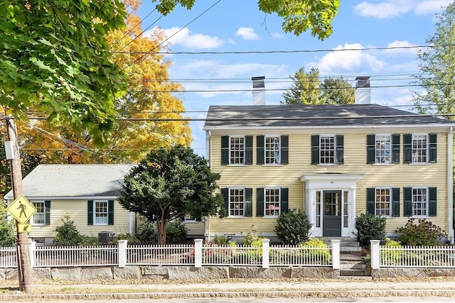 colonial inspired home with a fenced front yard, central AC, and a chimney