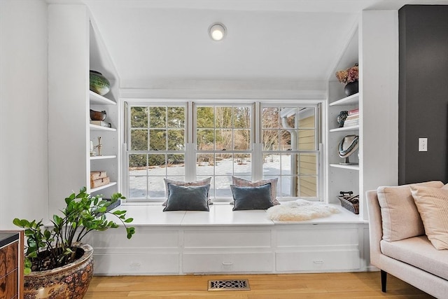 living area with vaulted ceiling, light wood finished floors, and visible vents