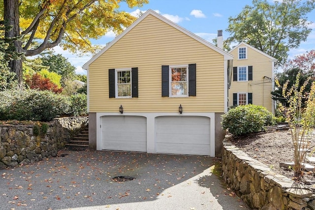 view of home's exterior with a garage, driveway, and stairs