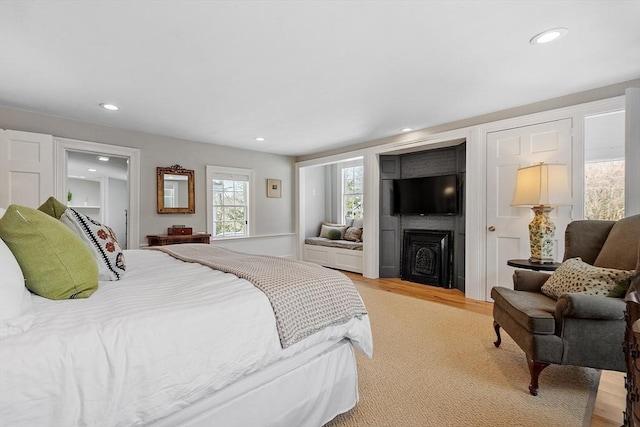 bedroom with light wood finished floors, a fireplace, and recessed lighting