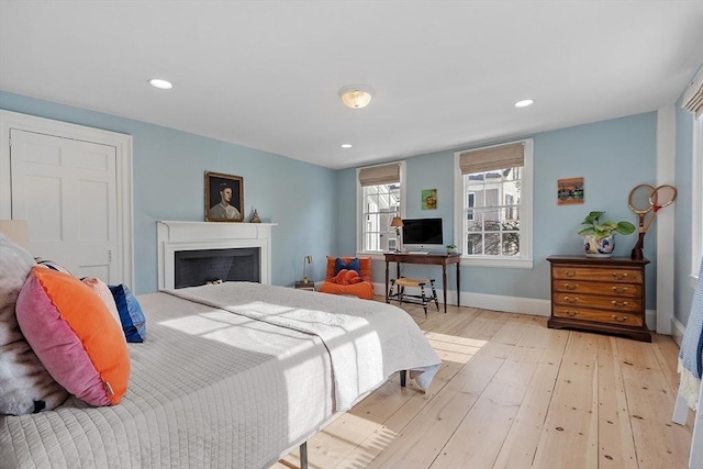 bedroom with wood-type flooring, a fireplace, baseboards, and recessed lighting