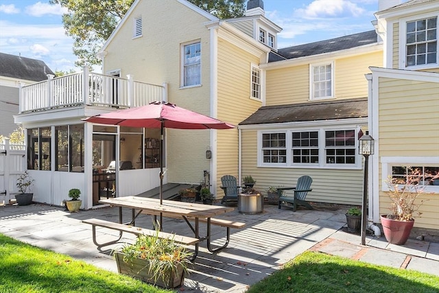 rear view of property featuring a sunroom, a patio, and a balcony