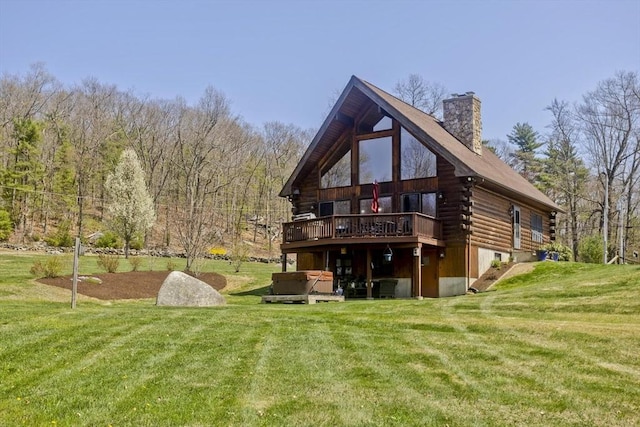 rear view of property featuring a chimney, a deck, a hot tub, log exterior, and a yard