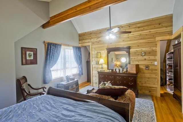 bedroom with vaulted ceiling with beams, wood finished floors, and wooden walls