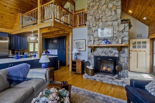 living room with light wood-style floors, high vaulted ceiling, a stone fireplace, a toaster, and wood ceiling