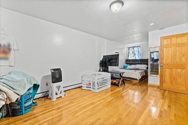 bedroom featuring hardwood / wood-style floors and a baseboard heating unit