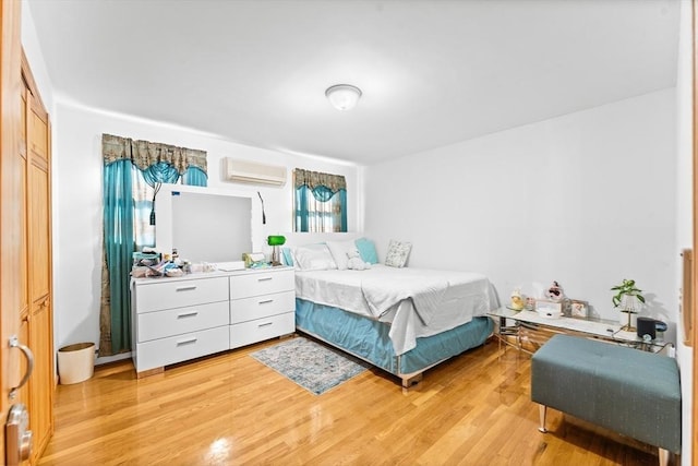 bedroom with a wall mounted air conditioner, a closet, and light wood-type flooring