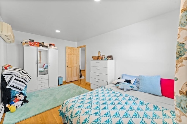 bedroom with an AC wall unit and light wood-type flooring