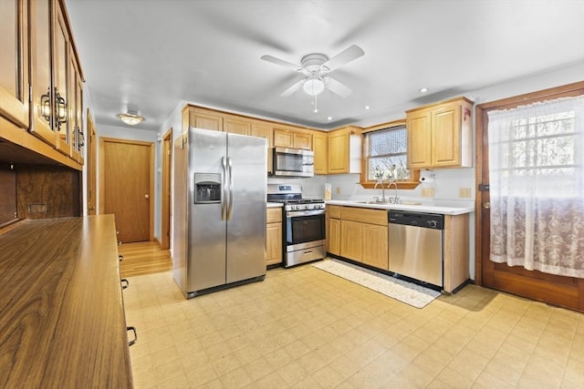 kitchen featuring stainless steel appliances, sink, light brown cabinets, and ceiling fan